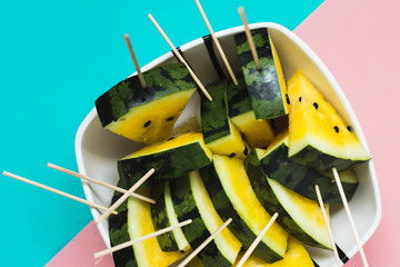 triangular slices of ice cream on a stick of ripe yellow watermelon in a plate