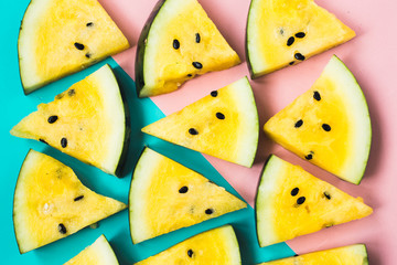 texture of triangular slices of ripe yellow watermelon on blue-pink background