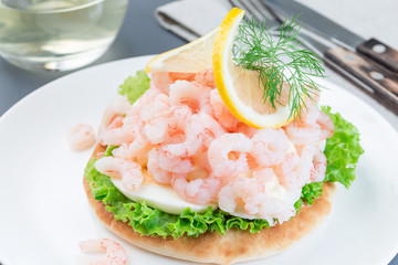 Traditional savory swedish sandwich with soft white bread vetekaka, lettuce, eggs, mayonnaise, shrimps, dill and lemon,  horizontal