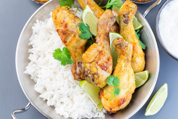 Indian chicken tandoori, marinated in greek yogurt  and spices, served with lime wedges, cilantro and basmati rice,  horizontal, top view