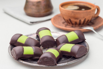 Swedish sweets punch rolls or punschrullar, covered with green marzipan, on a metal plate, served with coffee,  horizontal