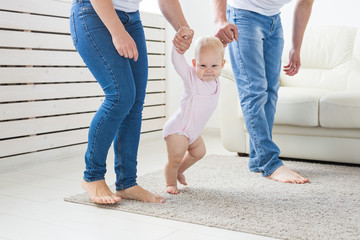 Family, children and parenthood concept - Parents teaching baby girl to walk