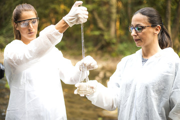 Scientist in protective suits takeing water samples from the river