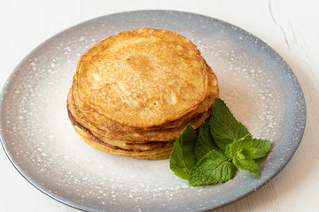 stack of American pancakes with some mint leaves in a gray plate on a wooden table. cooking concept.