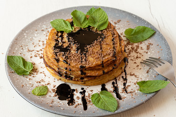 Stack of American pancakes with some mint and chocolate leaves in a gray plate on a wooden table. cooking concept.
