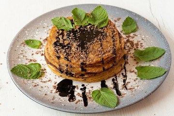 Stack of American pancakes with some mint and chocolate leaves in a gray plate on a wooden table. cooking concept.