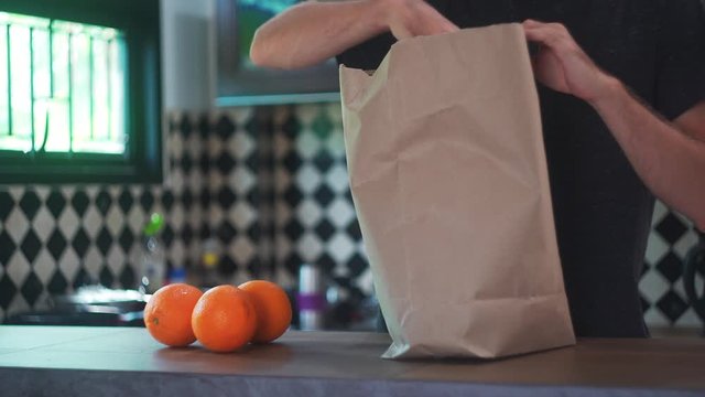 Young Man Taking Fresh Food Fruits and Vegetables From Brown Grocery Bag. 4K Close Up