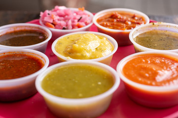 Several Mexican salsas in little cups on a tray - obrazy, fototapety, plakaty