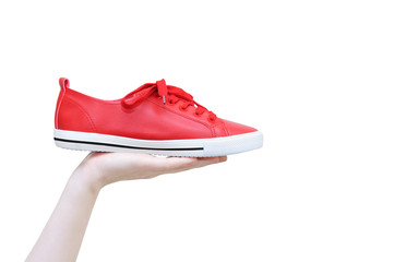 Red sneakers in the hand of a caucasian girl. White isolate.