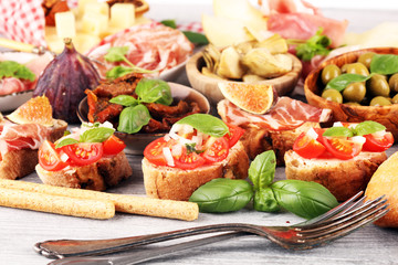 Italian antipasti wine snacks set. Cheese variety, Mediterranean olives, Prosciutto di Parma, tomatoes, artichokes