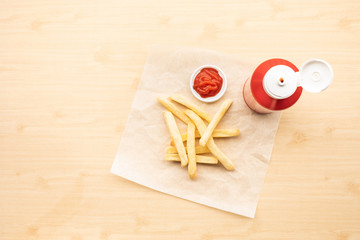 Fototapeta premium Top view of french fried with tomato sauce ( ketchup ) on wood table background.Fast food and unhealthy eating concepts