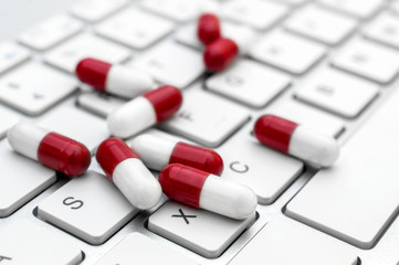 Pills on white keyboard. Close up. Online pharmacy concept.