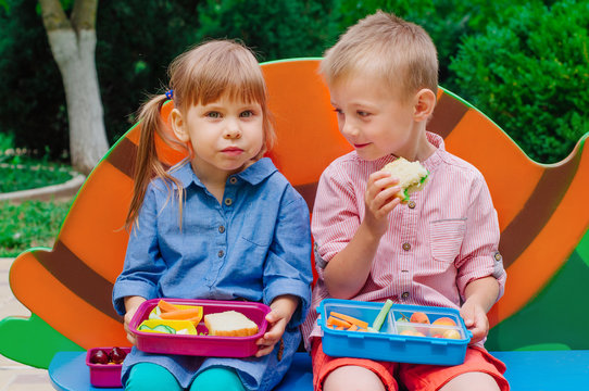 Elementary school students boy and girl eating lunch outdoor