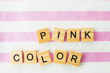 words pink color written in cubic letters on a pink striped textiles background, selective focus