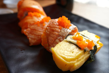 Sushi raw fish in front of rice set on black dish
