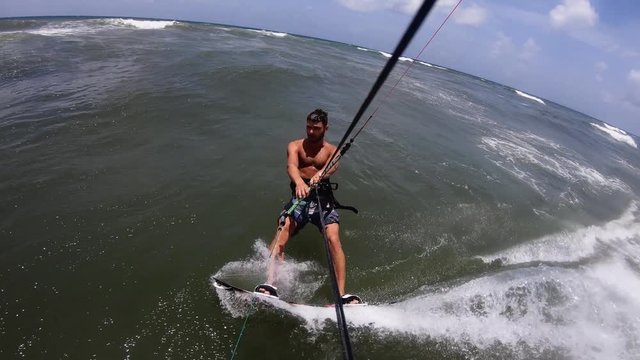 Gopro filming kite surfer riding waves.