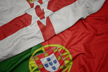 waving colorful flag of portugal and national flag of northern ireland.