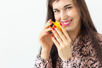 Playful young brunette woman holding in her hands a small yellow mug posing on a white background. Concept of morning coffee.