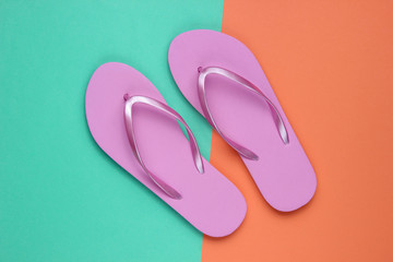 Trendy beach pink flip flops on coral blue paper background. Top view
