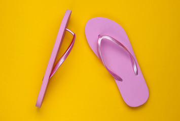 Trendy beach pink flip flops on yellow paper background. Top view