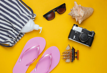 Summer still life. Beach accessories. Fashionable pink flip flops, bag, retro camera, sunblock...