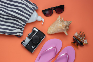 Summer still life. Beach accessories. Fashionable pink flip flops, bag, retro camera, sunblock...