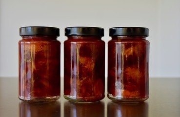 three glass jars in a row with delicious coarse home made plum jam