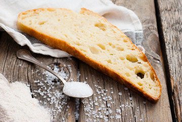 salt crystals on old spoon, slice of bread on old wooden