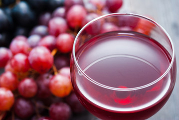 glass of red wine and grapes on black wooden table background