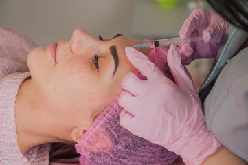 Obraz na płótnie Canvas Doctor cosmetologist makes Rejuvenating facial injections procedure for tightening and smoothing wrinkles on face skin of beautiful, young woman in beauty salon.Cosmetology skin care.