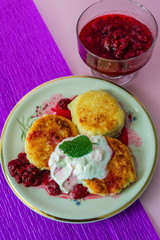cheesecakes with raspberry jam and sour cream on a plate on pink backround