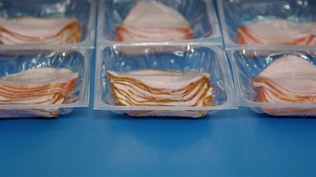 Packing of pork ham slices in small boxes in a meat processing factory  