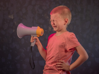 Child screaming into loudspeaker..Kid shouting through megaphone. Communication concept. Black background as copy space for your text