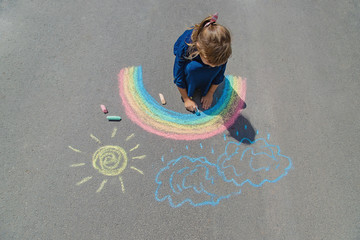 child draws with chalk on the pavement. Selective focus.