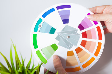 Define your color type. Female hands with neat, concise manicure rotate the color wheel.
