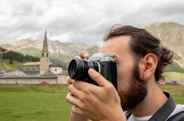 Young man take a photo in Livigno, Sondrio, Italy. Concept of tourism in italy alps