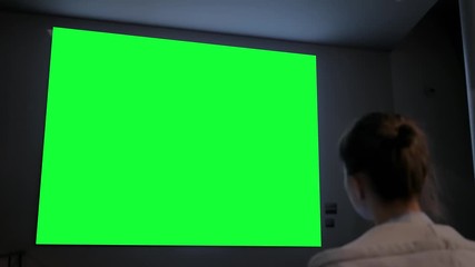 Green screen, technology, chroma key, futuristic, template, mock up, entertainment concept. Woman looking at large wall blank interactive green display at science exhibition, museum or cinema