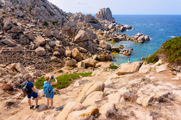 Couple looking at rocks on Capo Testa Sardinia