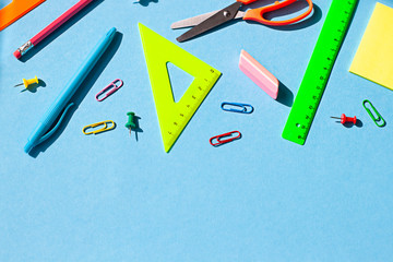 Colorful School stationery concept flat lay on the blue paper background. Top view. Copy space