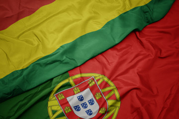 waving colorful flag of portugal and national flag of bolivia.