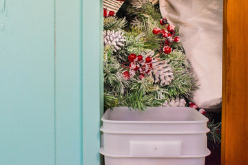 Christmas decorations in hawaii packed away for next Christmas, stored inside a closet with a wooden door, next to a vibrant light blue wall.