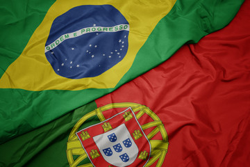 waving colorful flag of portugal and national flag of brazil.