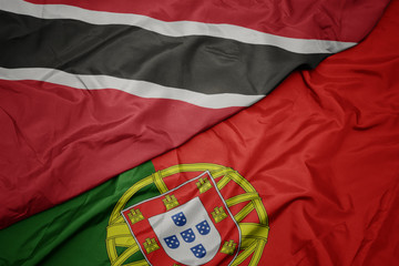 Fototapeta premium waving colorful flag of portugal and national flag of trinidad and tobago.