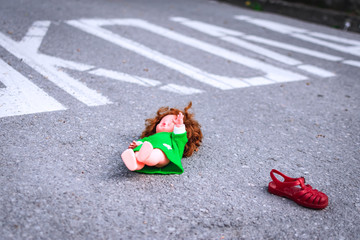 Old doll toy and red sandal in the middle of the road near school.