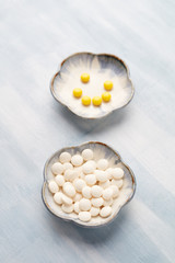 Hyaluronic Acid and Vitamin C tablets. Supplements to support collagen production. Concept for a healthy dietary supplementation. Bright wooden background. Copy space.