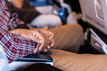 United hands of a couple sitting inside a plane