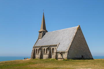 Fototapeta na wymiar Chapelle Notre Dame de la Garde in Etretat, old medieval catholic Norman church on the hill in a sunny summer day. Etratat, Normandy, France.