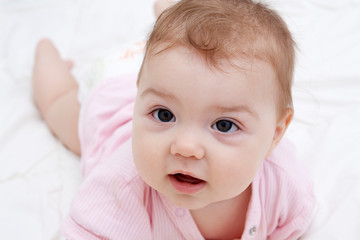 Portrait of a cute little baby lying on his stomach, who is learning to crawl