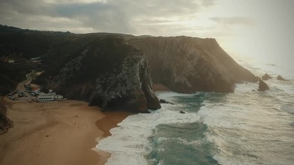Aerial view from a sandy beach at the sunset with an amazing cliff. Adraga beach Sintra, Portugal