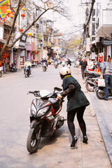 Woman riding moped in street of Hanoi